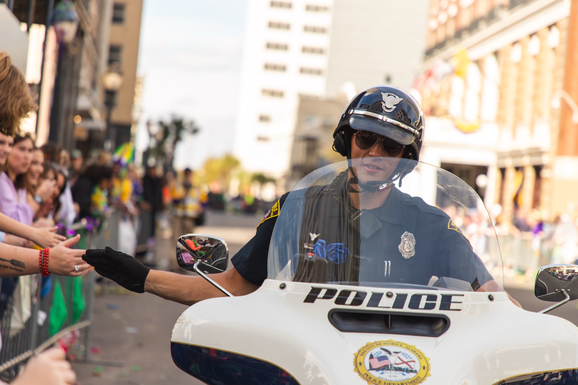 A motorcycle officer trades high-fives with the crowd along the route