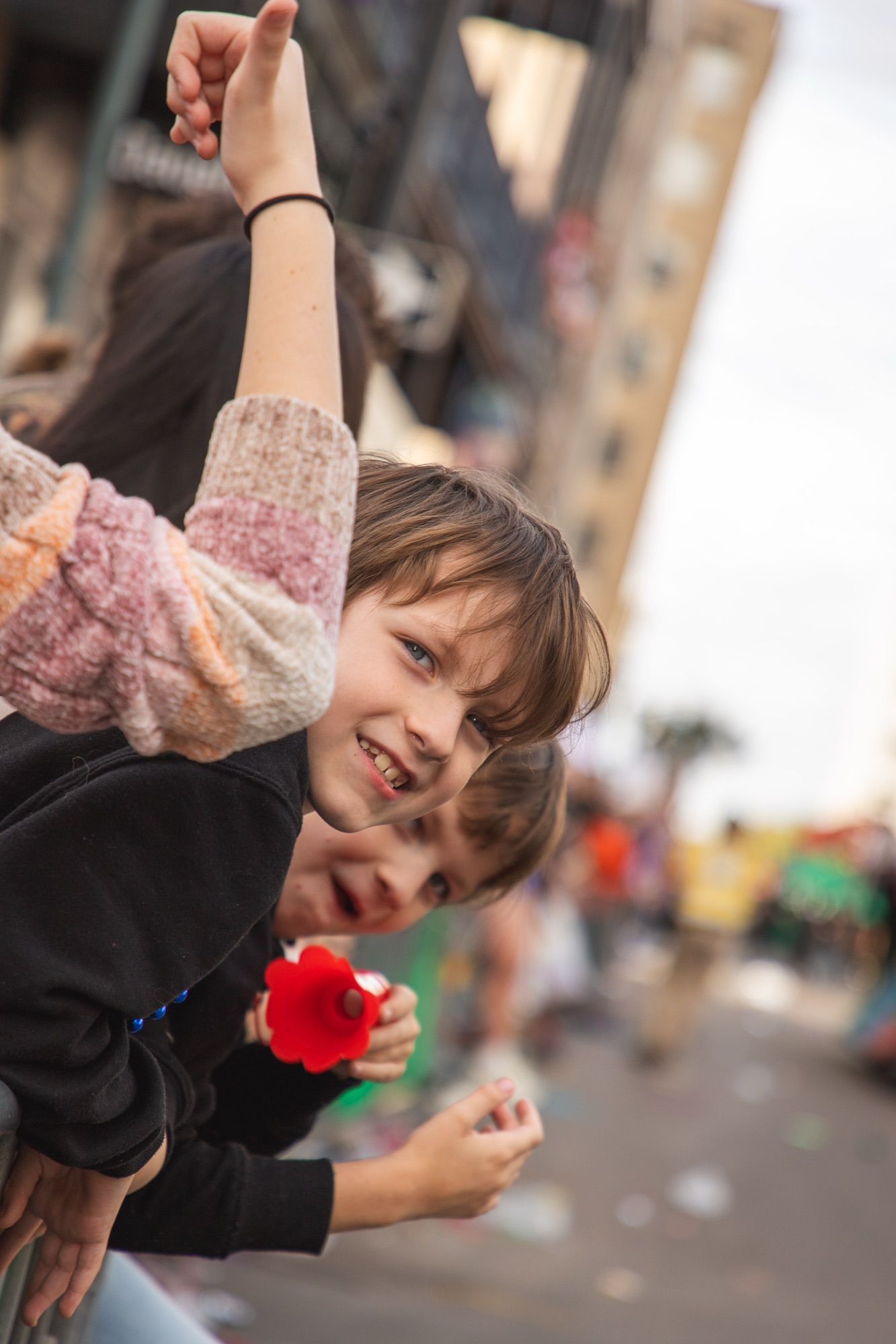 Two kids lean over the rail laughing during the parade
